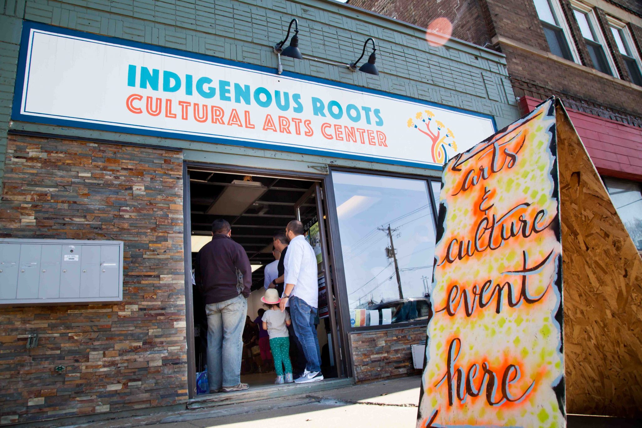 A group of people enter the Indigenous Roots Cultural Arts Center for an event
