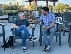 Two men talk in chairs at a park.