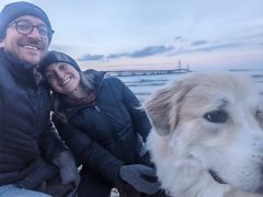 A man, woman, and dog with an icy lake in the background